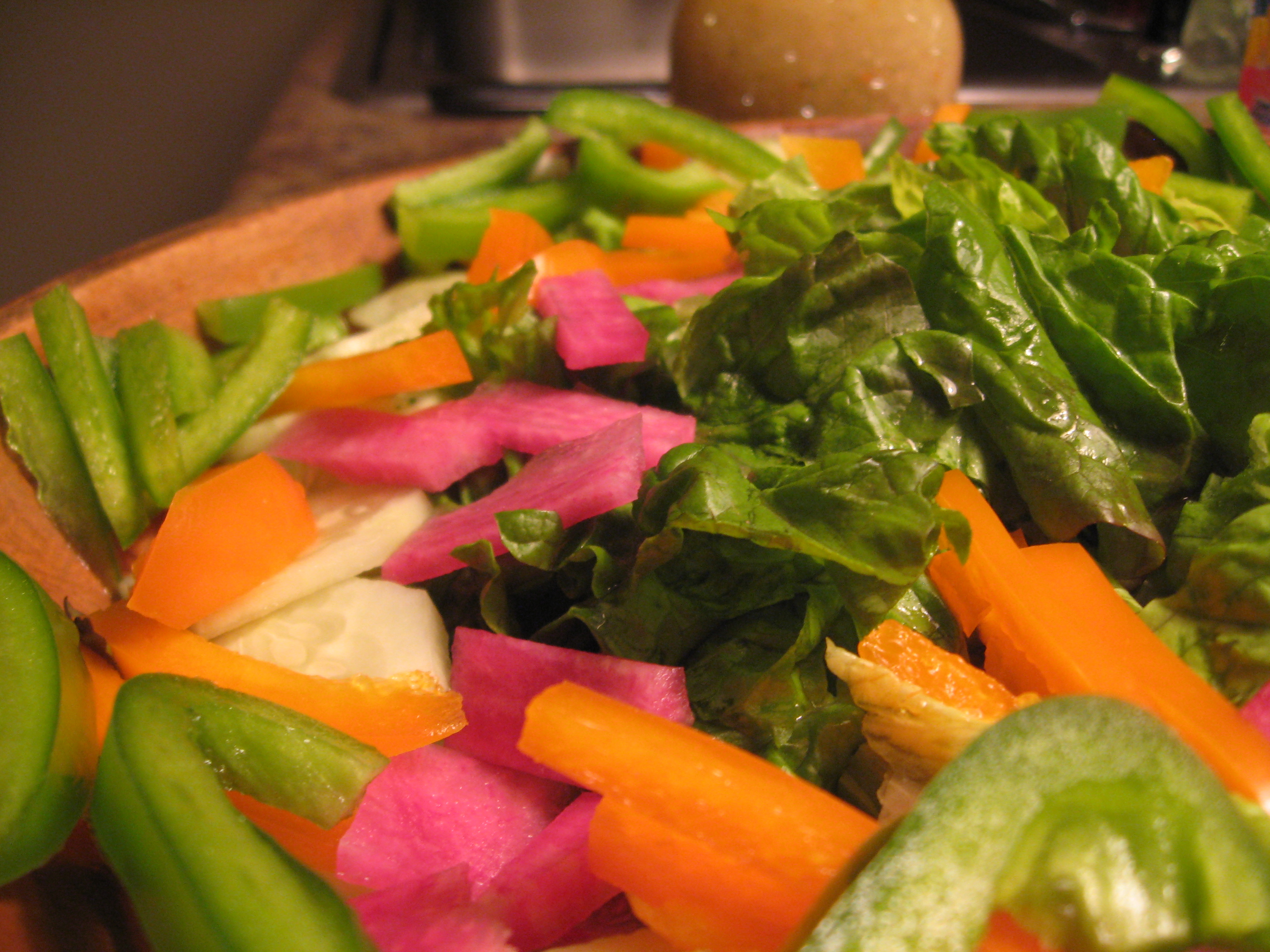 Watermelon radish in a salad of green leaf, cucumber, green and orange sweet pepper, carrots.