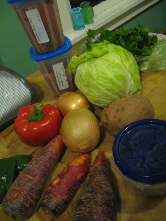 Piles of vegetables, including frozen tomatoes, crowd the counter.